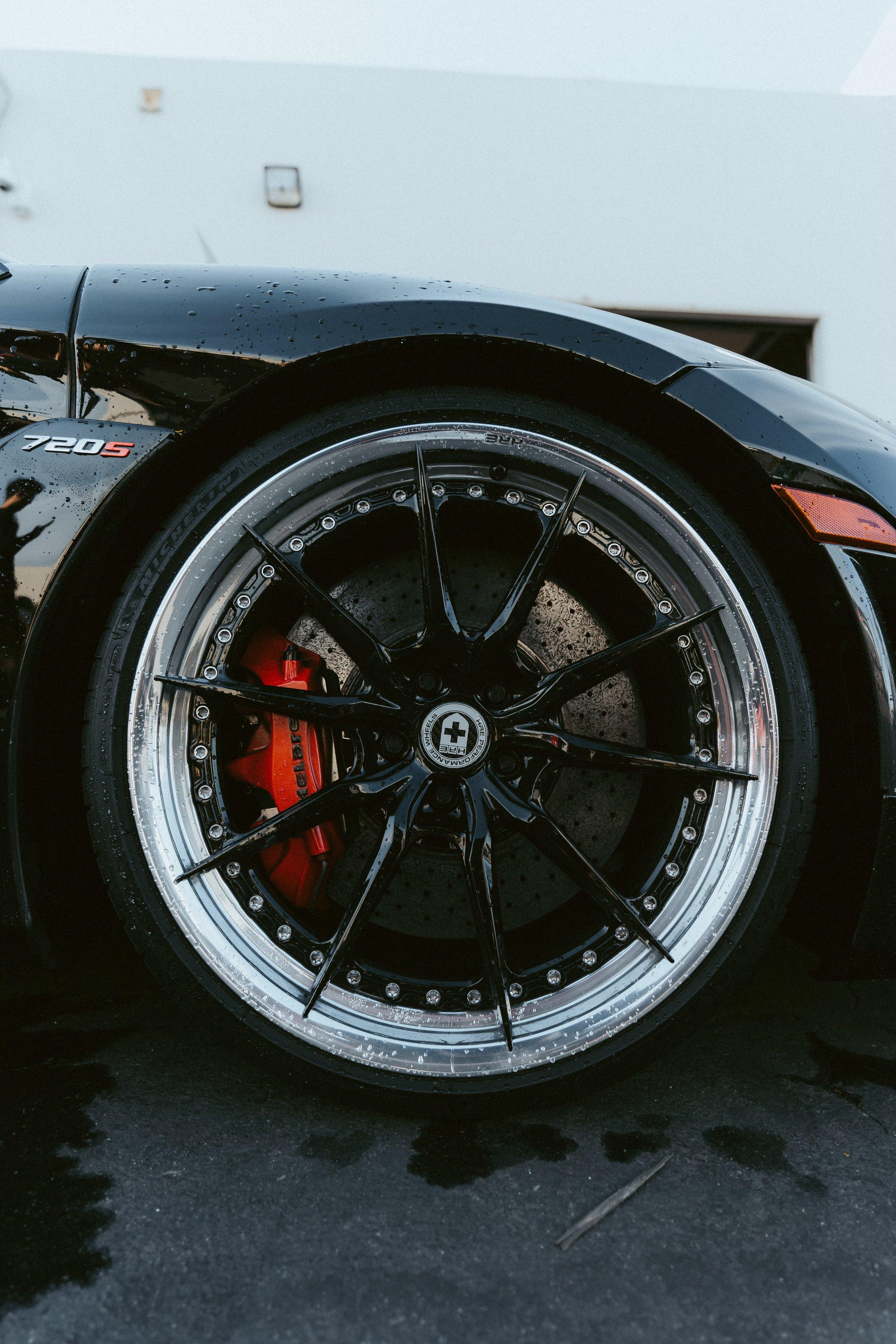 Forged McLaren wheel with a red caliper, wet from a fresh wash