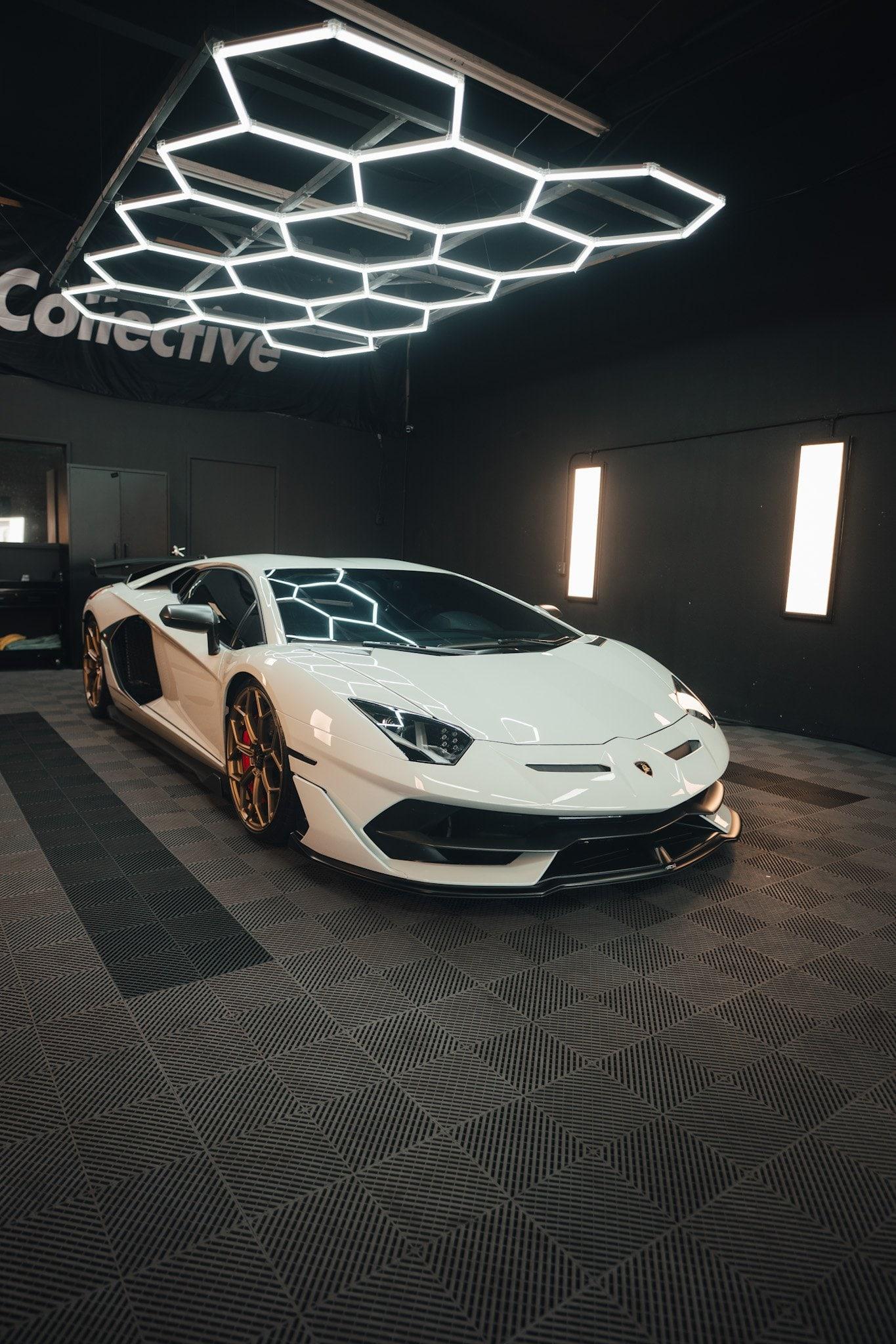 White Lamborghini Aventador with bronze wheels and red calipers in the studio bay